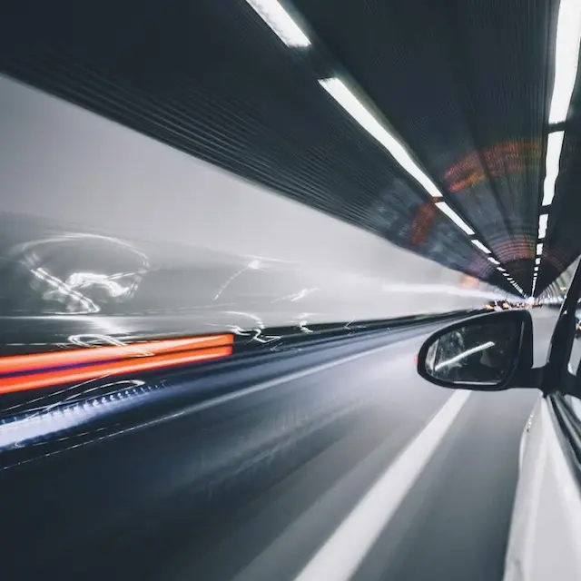 Imagen de un coche en un túnel, mostrando luces en movimiento y un efecto de velocidad, ideal para temas de automóviles y transporte.