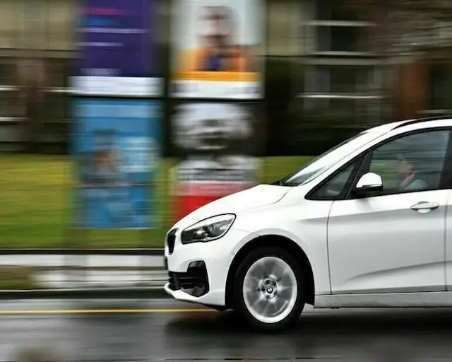 Coche blanco en movimiento en una carretera, mostrando su diseño moderno y aerodinámico, ideal para la conducción urbana y viajes.